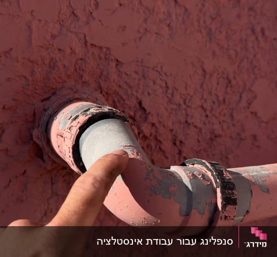 צינור מתכת עם צבע מתקלף על קיר ורוד